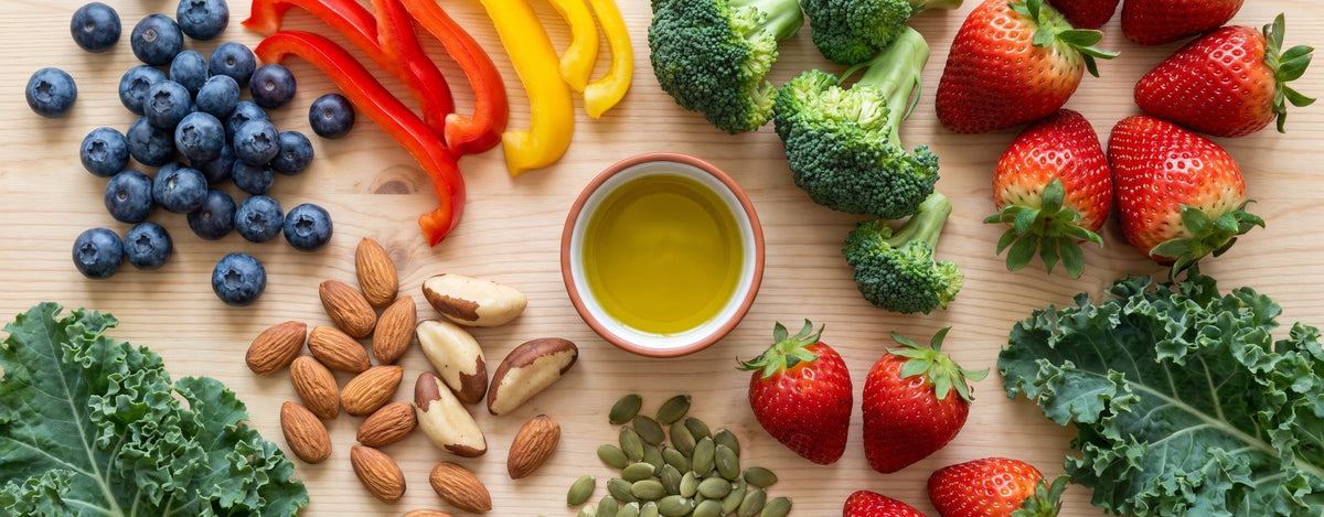 Heidelbeeren, Erdbeeren, Paprika, Brokkoli, Grünkohl, Mandeln, Paranüsse und Kürbiskerne auf einem Holztisch, Symbolbild für antioxidantienreiche Ernährung